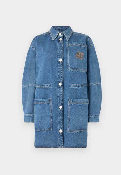 Casaco de denim em azul claro, apresentando um colarinho, mangas longas, botões de pressão e um bolso no peito com detalhes de costura em contraste.