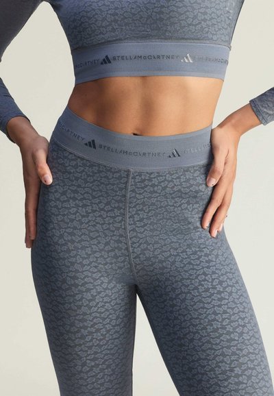 Grey activewear set featuring a fitted long-sleeve top and high-waisted leggings with a subtle leopard print and branded elastic bands.
