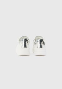 White sneakers with a textured metallic silver back, featuring a smooth sole and minimalistic design, suitable for casual wear.
