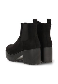 Botines de ante negros con un tacón alto y grueso, paneles laterales elásticos y tiradores en la parte posterior; textura suave y diseño de punta redonda.