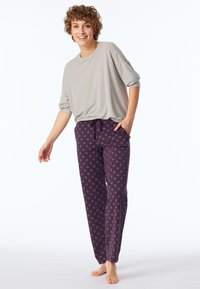 Ljusgrå oversized topp med kort ärm, kombinerad med lila byxor med dragsko som har ett cirkulärt mönster. Mjuk tyg, avslappnad passform, sidofickor.
