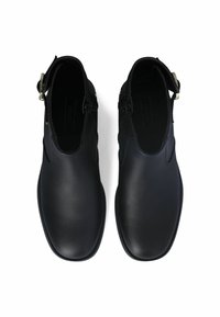 Scarpe in pelle nera con un design elegante, superficie liscia e dettaglio hardware regolabile sul lato. Interno spazioso per il massimo comfort.