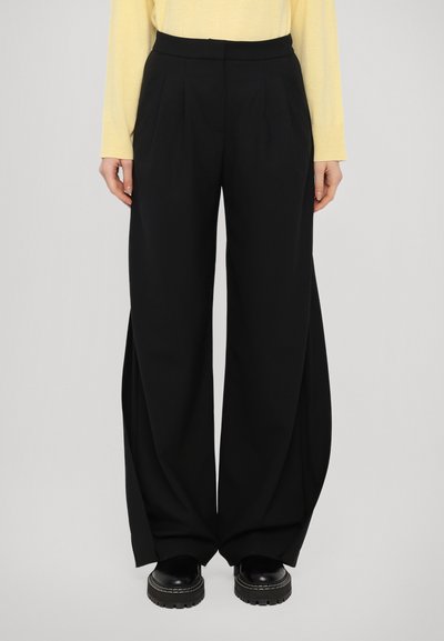 Schwarz weit geschnittene Hosen mit Falten, gefertigt aus einem glatten Stoff. Das Design zeichnet sich durch eine hohe Taille und eine verlängerte Silhouette aus.