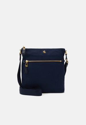 Sac bandoulière bleu marine avec sangle réglable, poche avant zippée, fermeture éclair dorée et détails du logo.