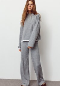 Hellgraues, weiches Strick-Loungewear-Set mit locker sitzendem Langarmoberteil und weiten Hosenbeinen in gerippter Struktur und mit einer weißen, geschichteten Verzierung.
