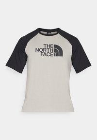 Camiseta de manga corta con cuerpo gris claro y mangas raglán negras. Presenta un audaz logotipo negro "THE NORTH FACE" en la parte frontal.