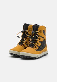 Bottes de randonnée jaunes et noires avec un dessus texturé, des lacets robustes et une semelle en caoutchouc conçue pour une traction sur terrain accidenté.