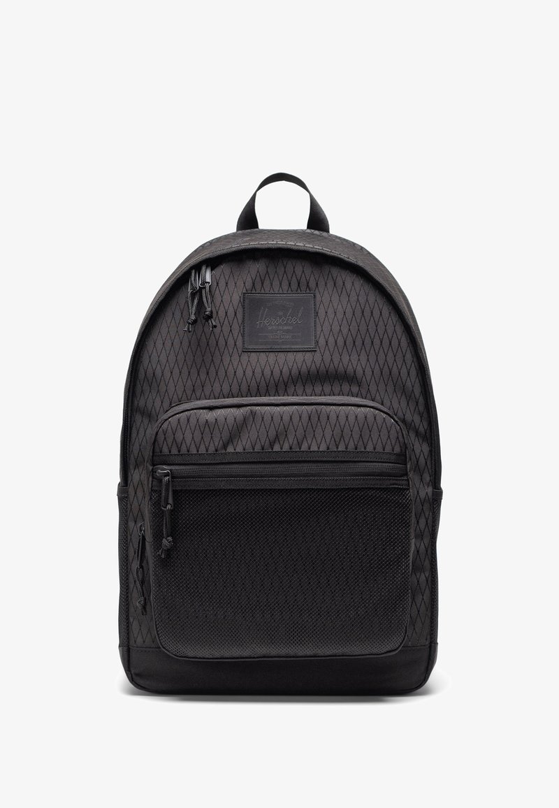 Sac à dos noir avec une texture à motif losange, poche frontale en maille, compartiments zippés et poignée de transport supérieure, présenté sur fond blanc.