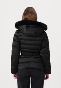 Black puffer jacket with a removable fur-lined hood, elastic waist detail, and horizontal quilted sections. Designed for warmth and comfort.