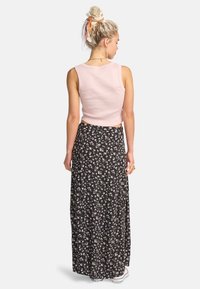 Lyserød cropped tank top og sort maxi nederdel med små hvide og lyserøde blomster. Nederdelen har et flagrende design og blød tekstur.