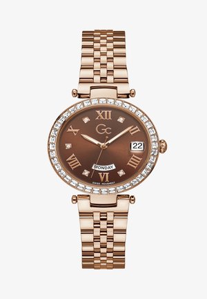Roze gouden horloge met een bruine wijzerplaat, Romeinse cijfers, kristalaccenten en een schakelen armband. Bevat een datum- en dagweergave.