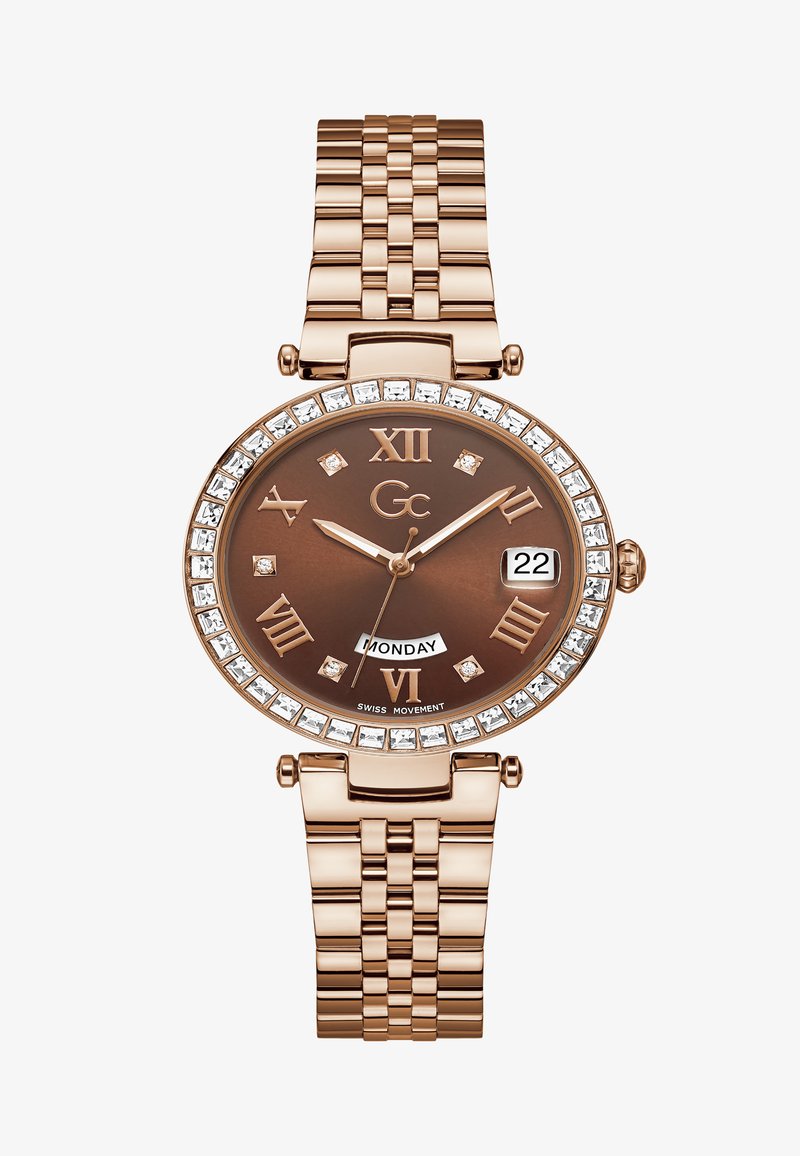 Roosa kuldne kell pruuni kelladialiga, rooma numbritega, kristallaktsentide ja linkidega käevõruga. Omab kuupäeva- ja nädalapäeva näidikut.