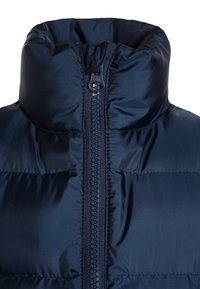 Tmavě modrá péřová bunda s vysokým límcem, zapínáním na zip a prošívanou strukturou. Má hladkou látku s jemným leskem.