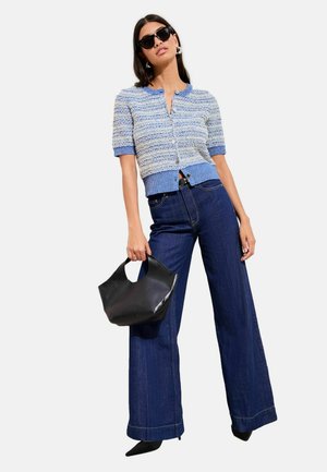 Cardigan tricotat texturat albastru și alb, cu mâneci scurte, cu nasturi în față; asortat cu blugi evazați cu talie înaltă, de culoare albastru închis, și o geantă neagră.