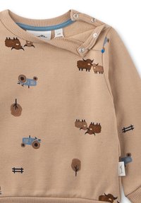 Beiger Pullover-Sweatshirt mit bedruckten Traktor- und Tiersymbolen in Braun und Blau. Verfügt über Druckknöpfe an der Schulter und einen gerippten Ausschnitt.