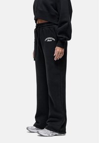 Zwarte sweatpants met elastische tailleband, gemaakt van zacht katoen, met een losse fit. Bevat het logo "GOODFORNOTHING" in het wit op de linker dij.