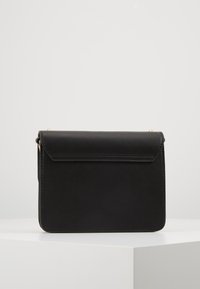 Borsa a tracolla nera in pelle con superficie liscia, forma rettangolare, chiusura a patta e tracolla in catena dorata rimovibile.