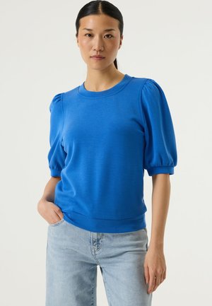 Blauw T-shirt met korte mouwen, opgepompte schouders en een ronde hals. Gemaakt van zachte stof, voorzien van een iets elastische zoom en een gladde textuur.