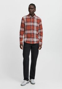 Rood en grijs geruit overhemd met knopen van lichtgewicht stof, met een klassieke kraag, lange mouwen en een rechte zoom, gedragen met donkere broek.