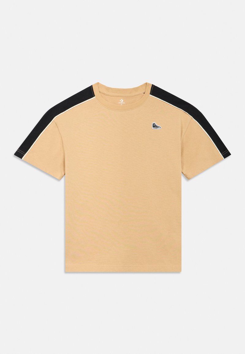 Μπεζ μπλουζάκι με μαύρες λεπτομέρειες στους ώμους, ριμπ λαιμόκοψη και μικρό λογότυπο σε πατς. Ομαλή υφή με ραφές αντίθετου χρώματος κατά μήκος των μανικιών.