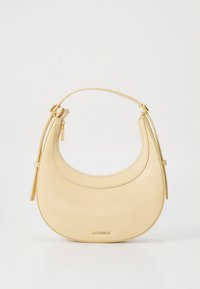 Mala em couro verniz bege com forma curva, um único cabo e detalhes em metal dourado. Apresenta fecho de correr e franjas laterais.