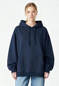 Sweat à capuche bleu marine avec une coupe ample, des poignets côtelés et une poche frontale. Fabriqué en tissu doux à la texture lisse.