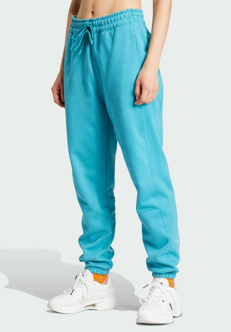 Turkise sweatpants lavet af blødt fleece, med elastisk talje og snørebånd, tapered manchetter og sidelommer. Hvide detaljer synlige.