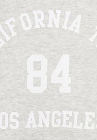 Hellgrauer Stoff mit weißem Blocktext in einem kollegialen Schriftstil, der "CALIFORNIA 84 LOS ANGELES" liest.