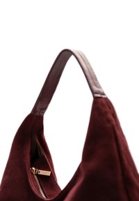 Burgundy suede shoulder bag with a smooth leather handle, featuring a zip closure and gold-tone hardware inside.