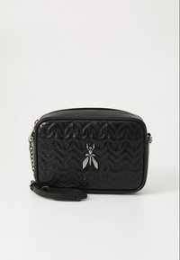 Schwarze gesteppte synthetische Tasche mit rechteckiger Form, silbernen Beschlägen und einem auffälligen dekorativen Käfer-Emblem auf der Vorderseite.