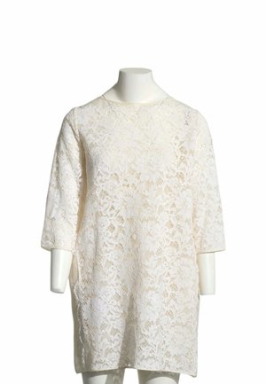 Robe en dentelle blanche avec manches trois-quarts, présentée sur un mannequin sans tête ni bras sur un fond blanc.
