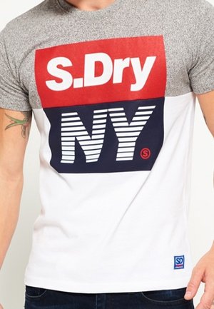 Kortærmet T-shirt med øverste del i grå, med en stor rød S.DRY-logo og mørkeblå "NY" trykt på en hvid krop. Blåt mærke ved kanten.