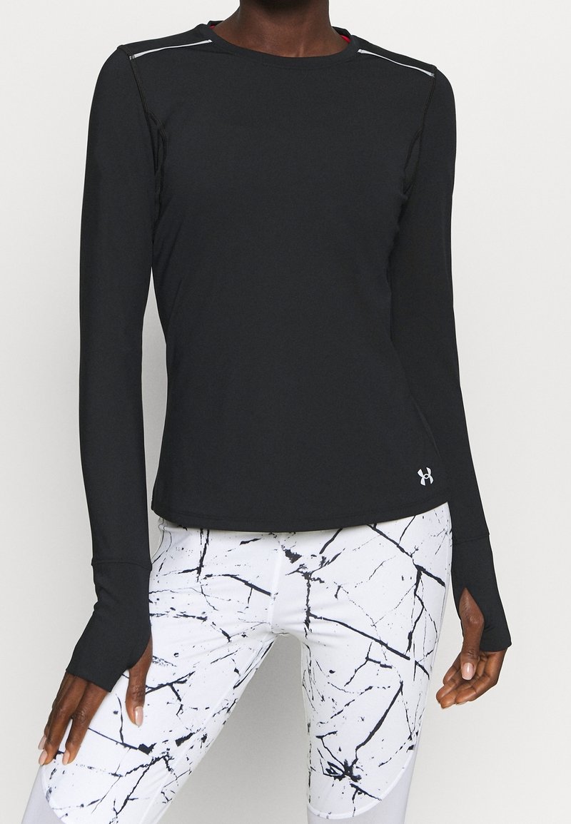 Svart långärmad sporttopp med kontrasterande vit söm, texturerad tyg och böjd fåll. Matchad med vita leggings med ett svart marmor-mönster.