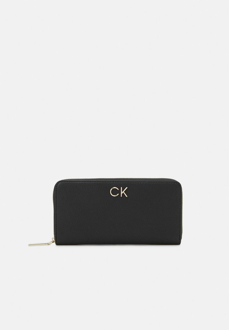 Svart läderplånbok med en strukturerad yta, som har en guld "CK"-logotyp på framsidan och ett blixtlås längs kanten.
