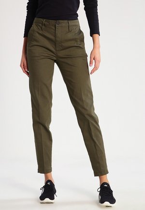 Olijfgroene chino's met een slim fit, voorzien van voorzakken, een knoopsluiting en een gladde katoenen stof. Zwarte sneakers maken de outfit compleet.