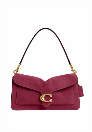 Sac à main en daim rouge avec un rabat incurvé, une fermeture dorée en forme de C, une courte bandoulière noire et rouge, et une petite étiquette sur le côté.