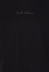 Sort bomulds T-shirt med rund halsudskæring, prydet med broderet tekst "Carlo Colucci" i hvid på brystområdet. Blød tekstur, minimalistisk design.