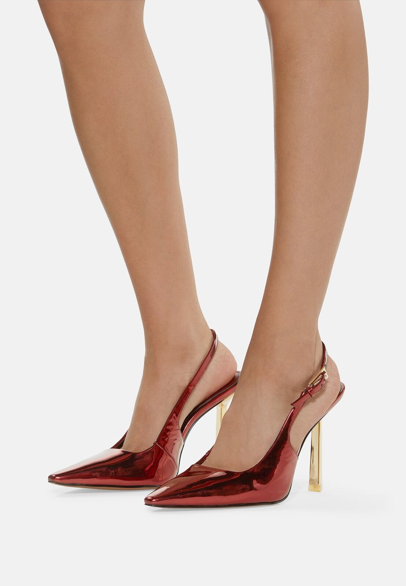 Rote Lackleder-Slingback-High-Heels mit spitzen Zehen und goldfarbigen Blockabsätzen. Besitzt ein elegantes Design und eine glatte Textur.