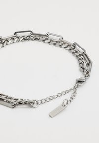 Silberne Kettenhalskette mit gemischten Gliederstilen, einschließlich flacher ovaler und rechteckiger Glieder, mit einem kleinen rechteckigen Anhänger in der Nähe des Verschlusses.