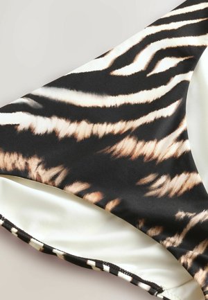 Slip da bagno a righe tigre nero e beige con una texture liscia, caratterizzato da un rivestimento interno a contrasto e bordi cuciti.