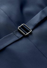 Tissu bleu marine avec une sangle réglable assortie fixée par une boucle rectangulaire en métal argenté.