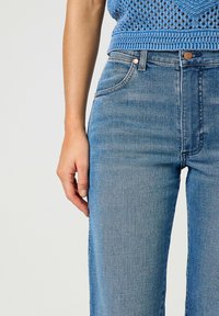 Jeans in denim blu a vita alta, con un classico design a cinque tasche, lavaggio chiaro e una leggera scoloritura. Il tessuto ha una trama liscia.