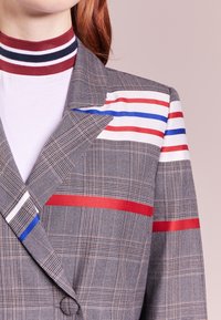 Giacca a quadri grigia con righe rosse, blu e bianche sulle maniche e sul colletto. Realizzata in tessuto testurizzato con una vestibilità su misura.