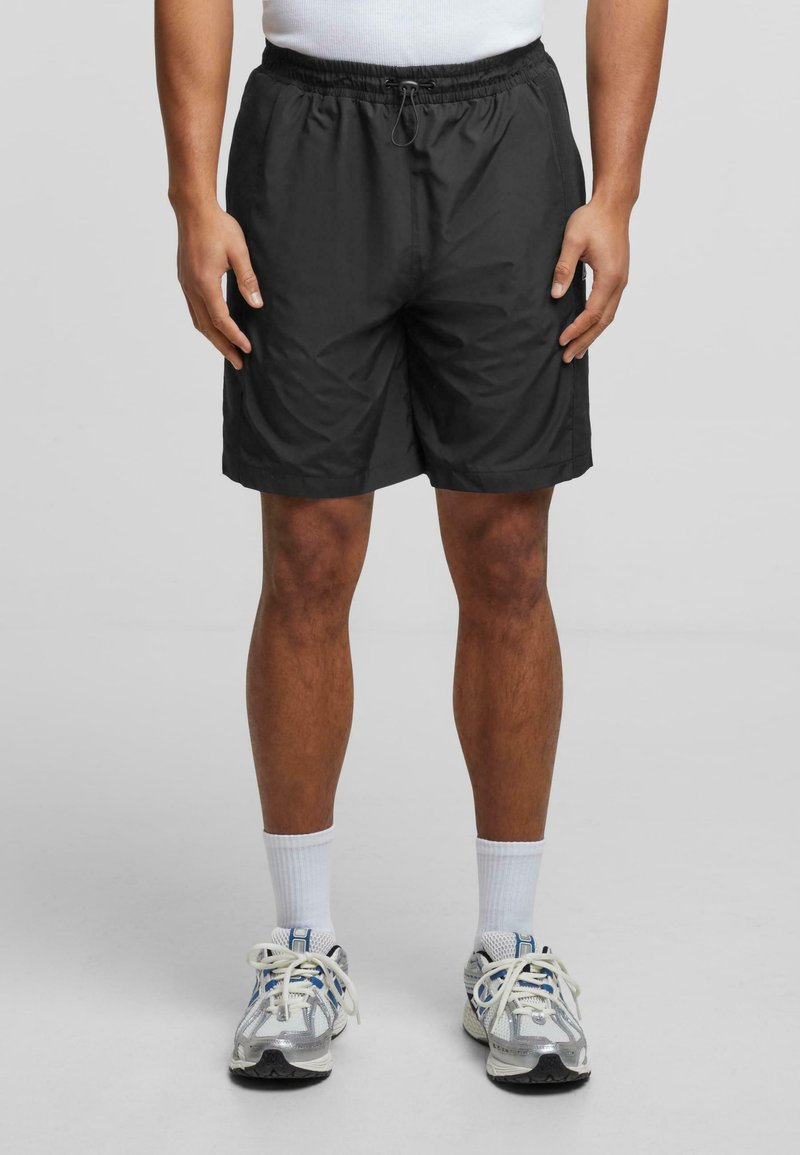 Shorts de sport noirs avec une taille élastique et un cordon de serrage, fabriqués en tissu léger ; conçus avec une coupe ample.