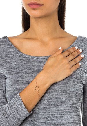 Roségouden armband met een hartvormige bedel, featuring een delicate ketting, op een grijze lange mouw top. Glad textuur en fijne details.