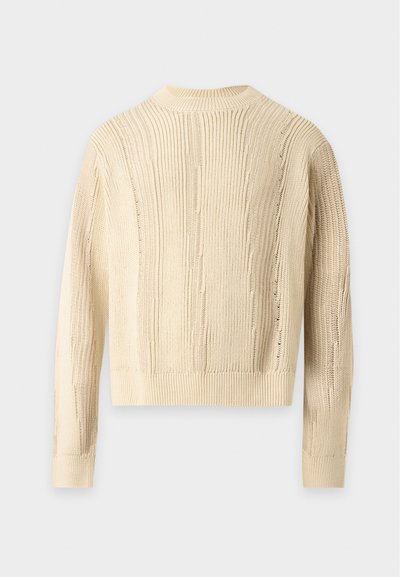 Pull en laine couleur crème à manches longues avec une texture côtelée verticale, vu de dos sur un fond gris clair.