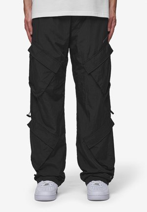 Black cargo pants with a wrinkled texture, multiple side pockets, elastic cuffs, and a loose fit, paired with white sneakers.