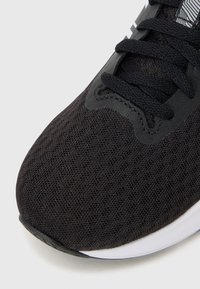 Black athletic shoe featuring a breathable mesh upper, textured surface, and lace-up closure with a contrasting white sole.