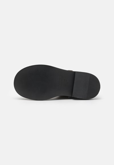 Talpa de pantof din cauciuc negru cu o textură netedă și un profil plat. Prezintă un toc mic și detalii de marcă gravate pe partea de jos.