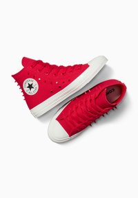 Sneaker alte e basse in tela rossa con suole in gomma bianca, dotate di un logo a stella, punte sul modello alto e lacci piatti.